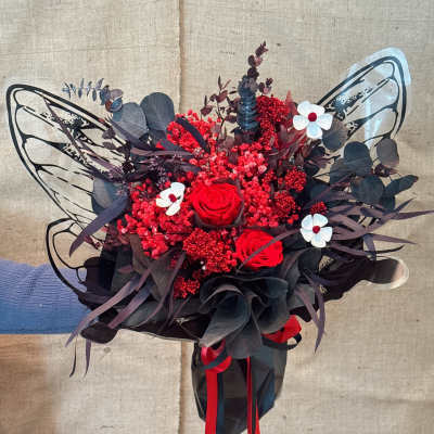 Red roses and dark foliage bouquet with butterfly wings and ribbon