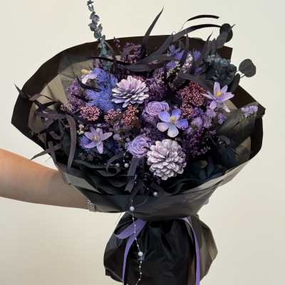 Purple bouquet wrapped in black paper with ribbon