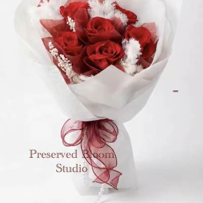 Bouquet of red roses wrapped in white paper with a red ribbon
