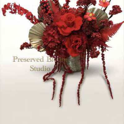 Red rose arrangement in a metallic vase with cascading berry stems