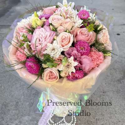 Bouquet of pink and white roses with mixed blooms wrapped in pastel paper