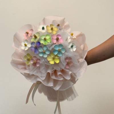 Pastel bouquet of small multicolored flowers wrapped in pale pink paper
