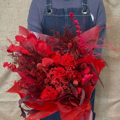 Large red bouquet of roses and decorative foliage wrapped in red paper