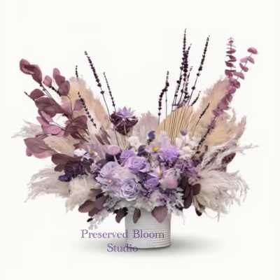 Lavender and mauve floral arrangement in a white container