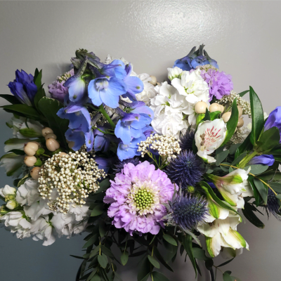 Bouquet of blue, white, and lavender flowers with dark greenery