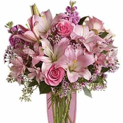 Tall pink and lavender bouquet of lilies and roses in a pink glass vase