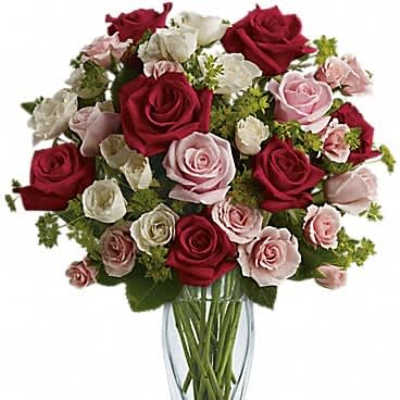 Arrangement of red, pink, and white roses in a tall clear glass vase