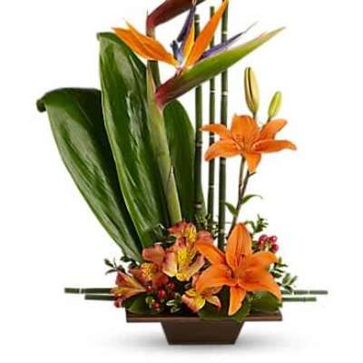 Tropical arrangement with birds of paradise and orange lilies in a low rectangular container.