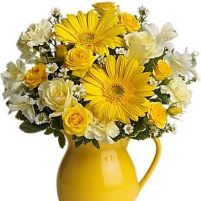 Yellow and white flower arrangement with gerbera daisies and roses in a yellow ceramic pitcher