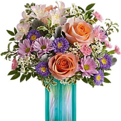 Peach roses with pink and purple mixed flowers arranged in a teal glass cylinder vase