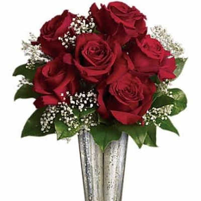 Arrangement of red roses with white filler flowers in a tall silver vase