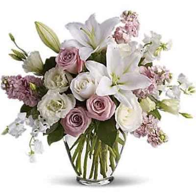 Arrangement of white lilies and pale pink and white roses in a clear glass vase