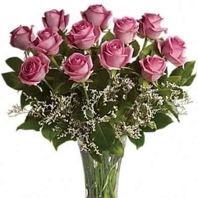 Arrangement of pink roses with white filler flowers in a clear glass vase