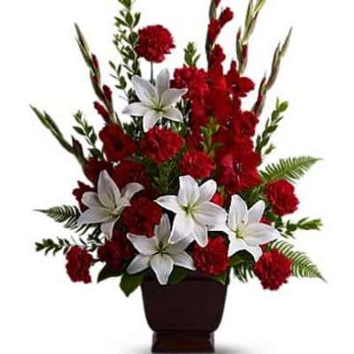 Tall red and white floral arrangement with lilies and carnations in a dark square vase