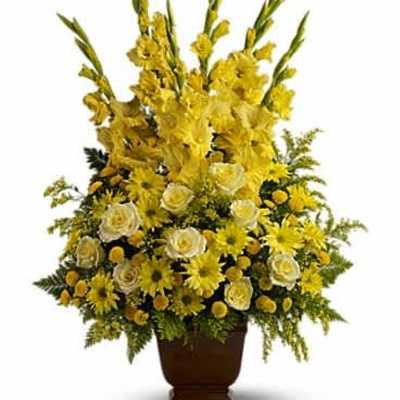 Tall yellow and white flower arrangement with roses and gladiolus in a brown pedestal vase
