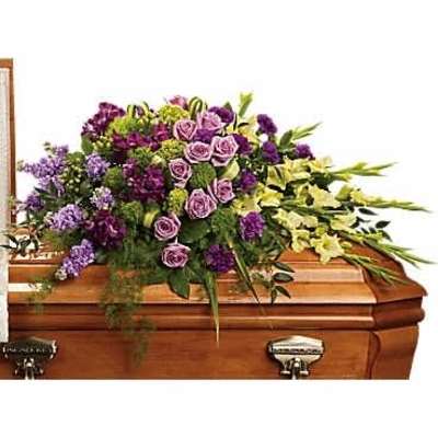 Purple and yellow mixed flower casket spray arranged on a wooden casket