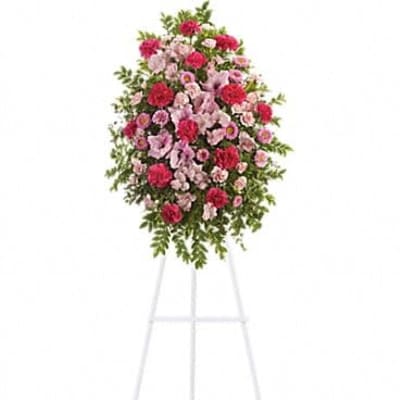 Tall pink and red standing spray of carnations and mums displayed on a white metal easel