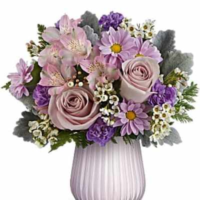 Pastel bouquet of pink roses, lavender daisies, and alstroemeria in a ribbed lavender glass vase