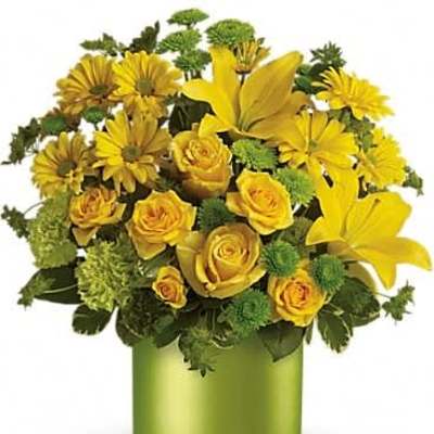 Arrangement of yellow roses, lilies, and daisies in a green cylinder vase