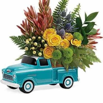 Yellow roses and mixed blooms arranged in a teal ceramic pickup truck container