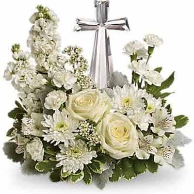 Low white sympathy arrangement with roses, mums, carnations and a crystal cross in the center.