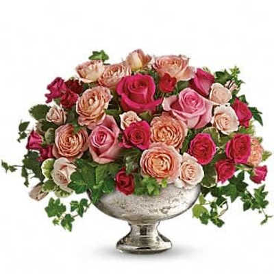 Low arrangement of pink, peach, and red roses in a silver pedestal bowl
