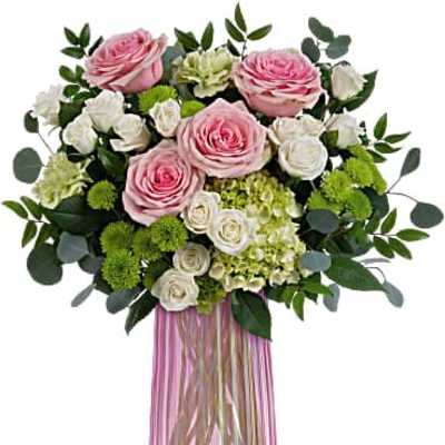 Pink and white rose arrangement with green accents in a tall ribbed pink glass vase