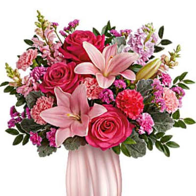 Pink lilies, roses, and carnations arranged in a fluted light pink vase
