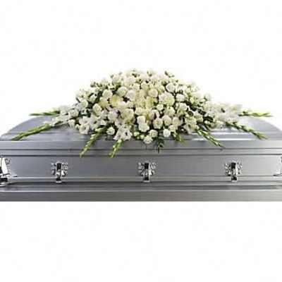 Long white floral casket spray arranged on a silver casket