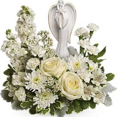 Low white floral arrangement with roses and carnations surrounding a white ceramic angel figurine