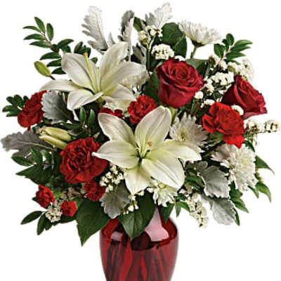 Arrangement of white lilies, red roses, red carnations, and white mums in a red glass vase