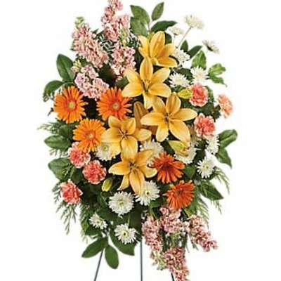 Standing spray with yellow lilies, orange gerberas, white mums, and pink flowers on an easel