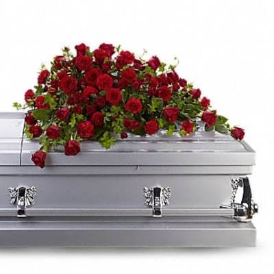 Red rose casket spray arranged on top of a silver casket