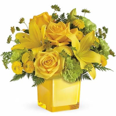 Yellow roses and lilies arranged in a square glass vase