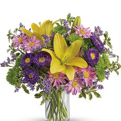 Bouquet of yellow lilies and pink daisies in a clear glass vase