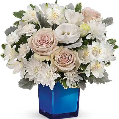 White and blush flowers arranged in a blue glass vase