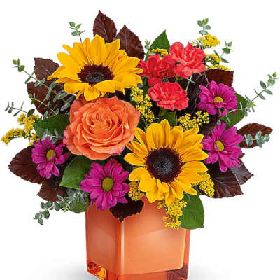 Bouquet of sunflowers, roses, and purple daisies in an orange vase