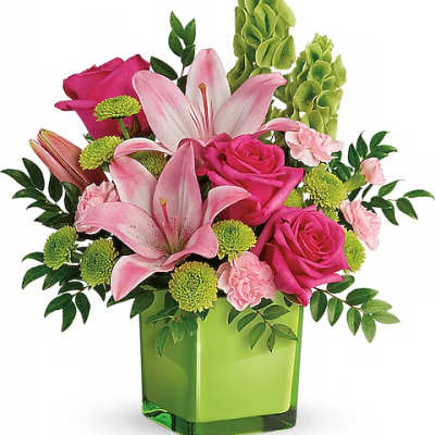 Pink lilies and roses arranged in a green square vase