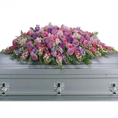 Large pink and purple floral casket spray on a gray casket