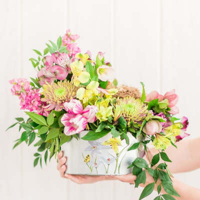 Pink and yellow mixed bouquet in a decorative tin container