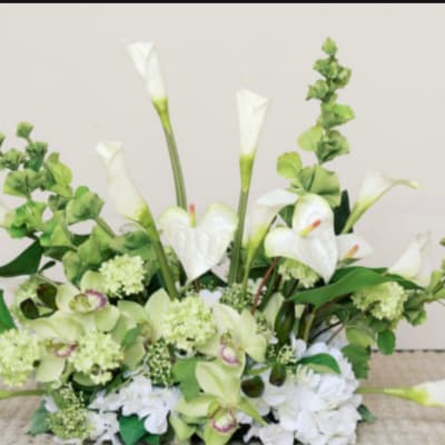 White calla lilies and pale green orchids in a low floral arrangement