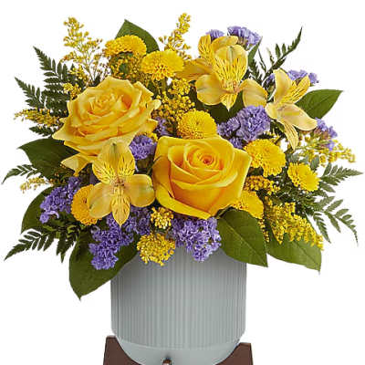 Yellow roses and purple flowers arranged in a vase on a stand