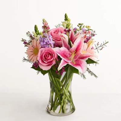 Pink roses and lilies arranged in a clear glass vase