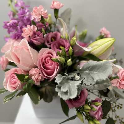 Pink roses and purple blooms arranged in a white vase