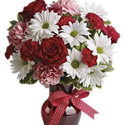 Red and white mixed bouquet in a dark vase with a polka-dot ribbon