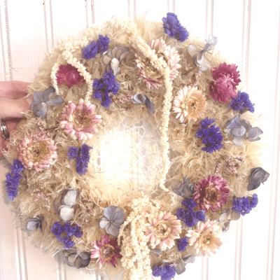 Dried floral wreath with purple and pink flowers on a straw base