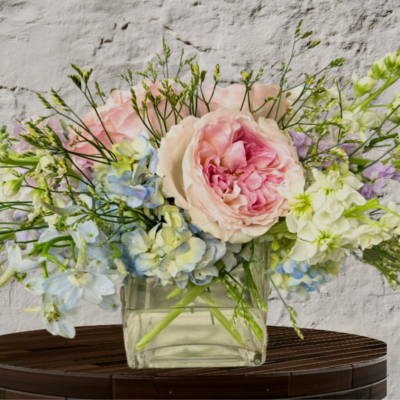 Pastel bouquet of pink and blue flowers in a clear glass vase