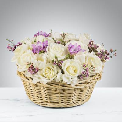 White roses and purple flowers in a wicker basket