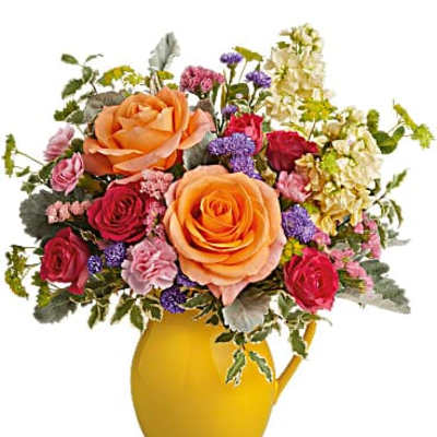 Bouquet of orange and red roses in a yellow pitcher vase