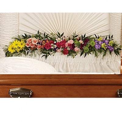 Colorful floral spray arranged across a wooden casket